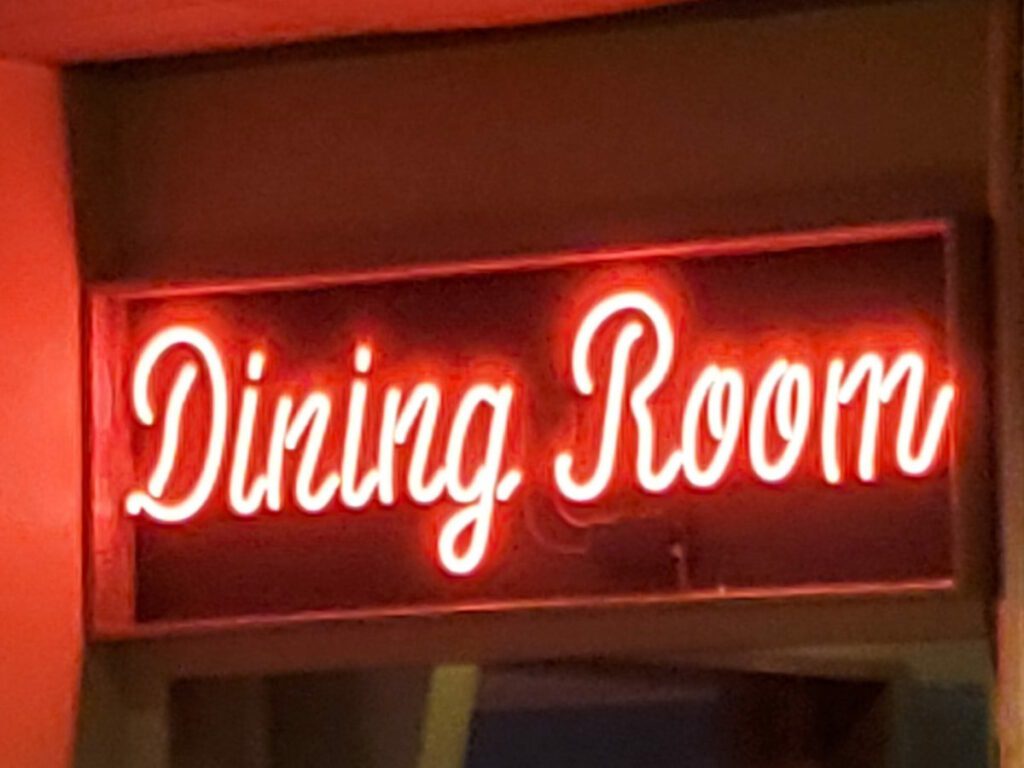 Neon red sign in the NIghtingale Restaurant that says "Dining Room"