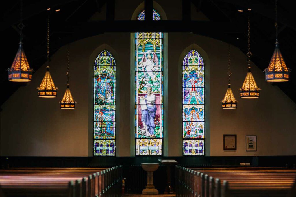 interior of a church with tained glass, pews, and lights