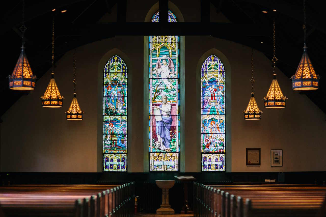 interior of a church with tained glass, pews, and lights