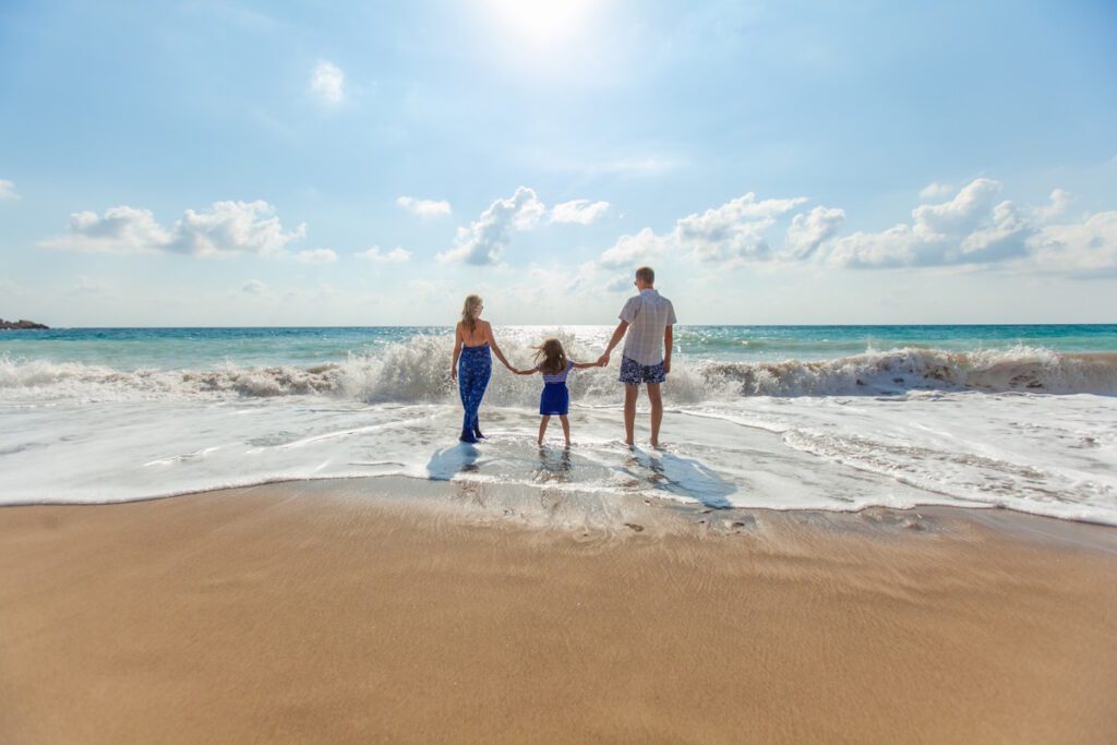 man, woman, and small female child in front of the ocean