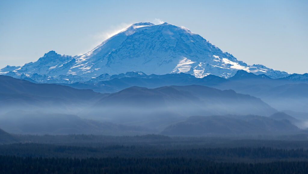 A view of Mount Rainier near Seattle with layers of foothills shrouded in mist in front