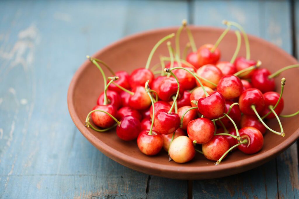 A ripe sweet cherries in a ceramic bowl on a rustic background