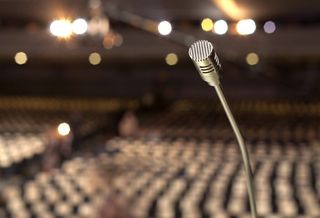 microphone closeup with blurry auditorium in background